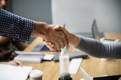 A close-up of two professionals shaking hands over a table.