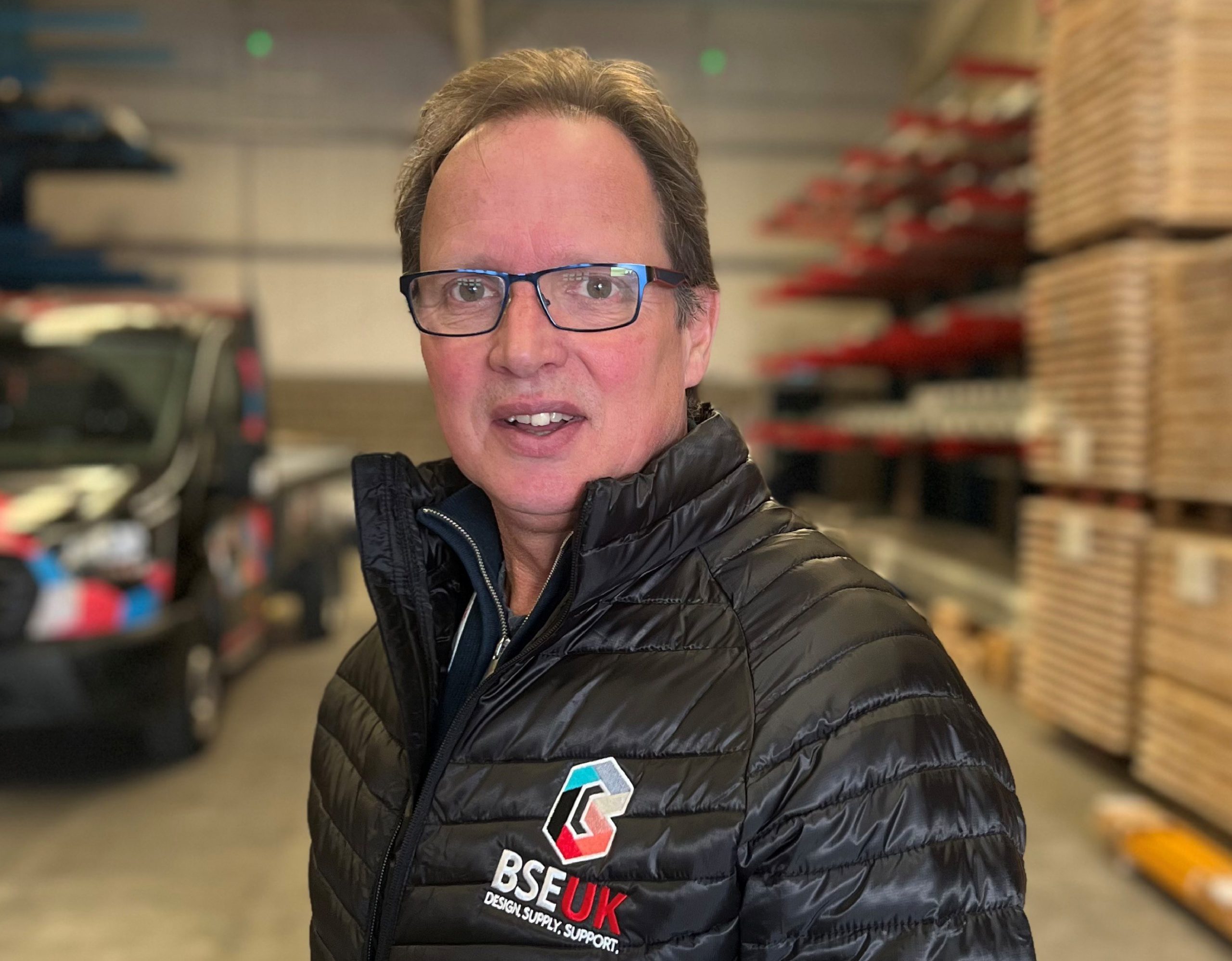 Jerry Hubble is BSE UK's Office Fit-Out Manager, photo taken in a warehouse with racking behind