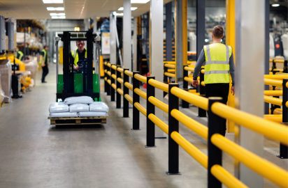Sturdy yellow and black safety railings installed along a warehouse floor to protect workers and inventory.