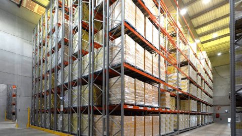 A view of expansive, multi-level pallet racking densely packed with inventory boxes in a large distribution center.
