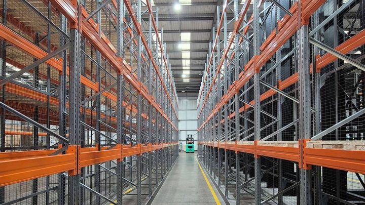 Industrial warehouse interior aisle with empty storage racking systems and high ceilings in a large distribution facility.