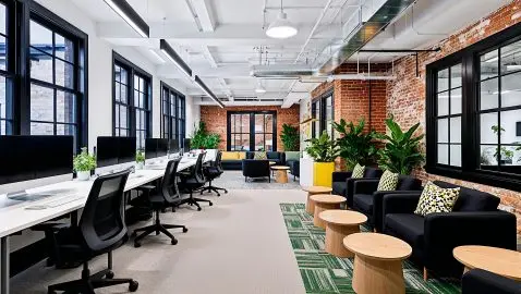 Spacious open office featuring modern design, exposed brick, and greenery. AI generated image