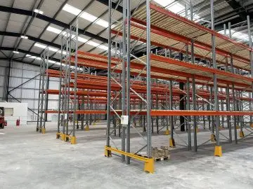 Industrial warehouse interior with empty storage racking systems and high ceilings in a large distribution facility.